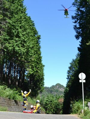 負傷者をヘリで救出しようとする消防隊員ら