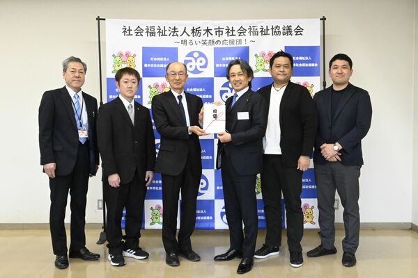 赤羽根会長（左から３人目）に目録を手渡した松島会長（同４人目）