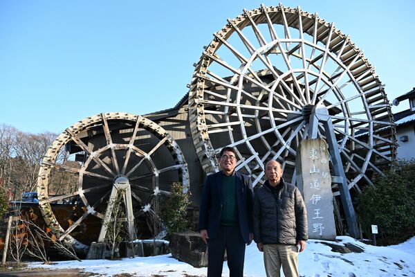道の駅のシンボルになっている巨大水車の前に立つ橋本社長（右）と沼井常務＝那須町伊王野