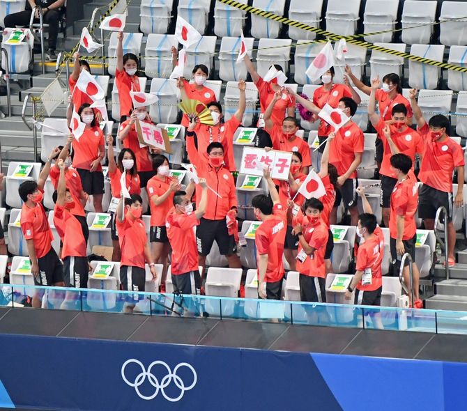 競泳の日本選手団は感染症対策で1席間隔を空けながら日の丸とプラカードを持ち、出場選手にエールを送った。上から2列目右から2人目は萩野公介=8月1日、東京アクアティクスセンター