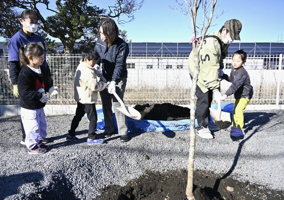 建設中の複合施設の前で植樹をする園児たち