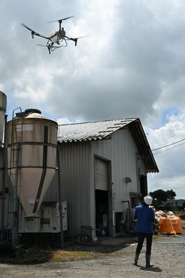ドローンによる牛舎の屋根への遮熱剤散布の様子＝７日午前、高根沢町平田