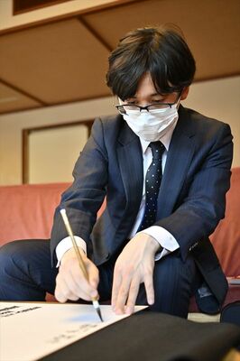 揮毫する伊藤七段＝16日午後４時45分、日光きぬ川スパホテル三日月