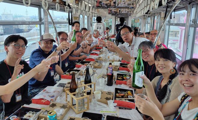貸し切りのモノレールで本県の地酒を味わう参加者＝23日午後、大阪府