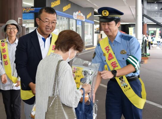 来店客に啓発ステッカー入りのナシを手渡す星野署長（右）と星野町長（左）
