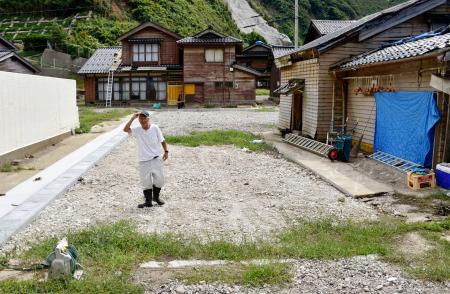 　地震と豪雨による被災からの復旧が進まない石川県輪島市門前町深見地区の集落で、自宅が全壊し、更地になった場所に立つ男性＝１２日