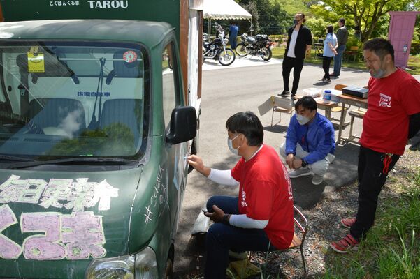 仲間たちとこくばんくるまに絵を描く佐原さん（右）