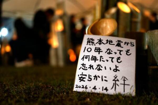 熊本地震の「前震」から10年となり、犠牲者を悼みともされた竹灯籠のそばに置かれたメッセージ=14日夜、熊本県益城町