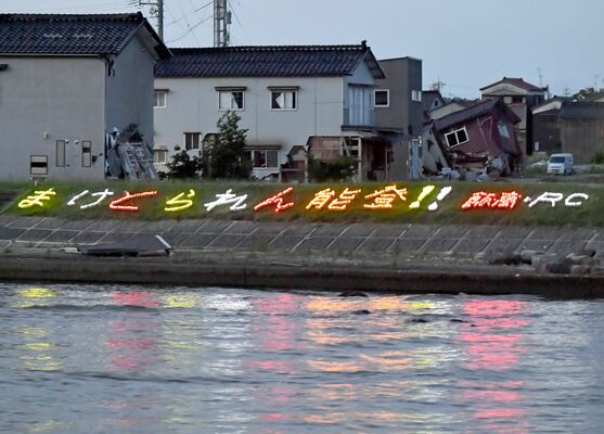 地元の飯田高の生徒が設置したLEDライトのメッセージ。損壊した住宅の近くで夜間点灯している＝１日午後７時50分、石川県珠洲市飯田町
