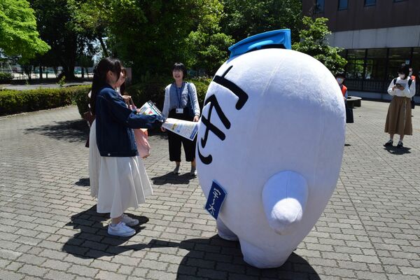 啓発活動に参加し学生にチラシを配布する「宇～太」＝10日午前、宇都宮大
