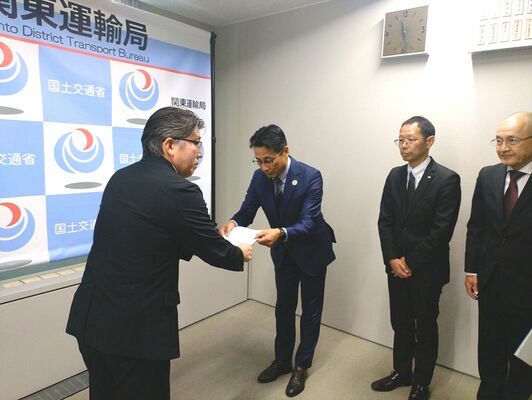 担当官(左)に計画書を提出した宇都宮市、芳賀町、ライトレールの代表者=29日午前11時半、横浜市中区の国土交通省関東運輸局、宇都宮市提供