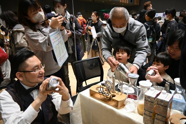 ジュースの入ったシェーカーを振ってバーテンダーの体験をする子どもたち