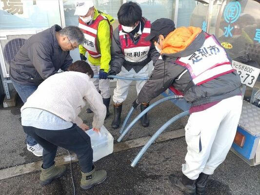 のと里山空港で避難者が持参した容器に給水する職員たち（足利市提供）