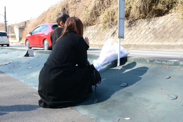 事故現場付近で手を合わせる佐々木さん=14日午前、宇都宮市下栗町