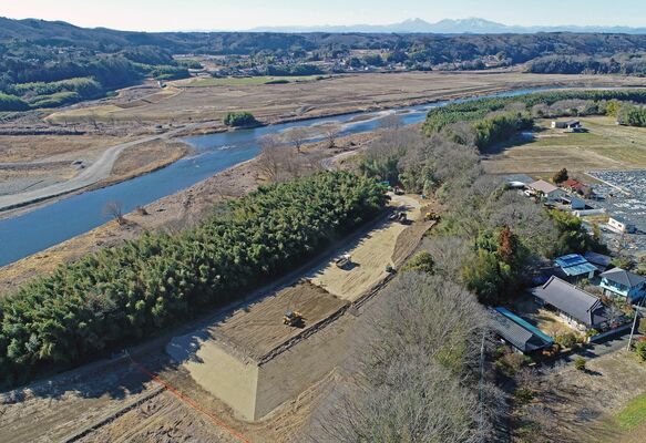 那珂川流域の民家のそばで建設が進む霞堤。周辺は防災集団移転の対象地域となっている＝16日午後１時45分、那須烏山市下境、ドローンから