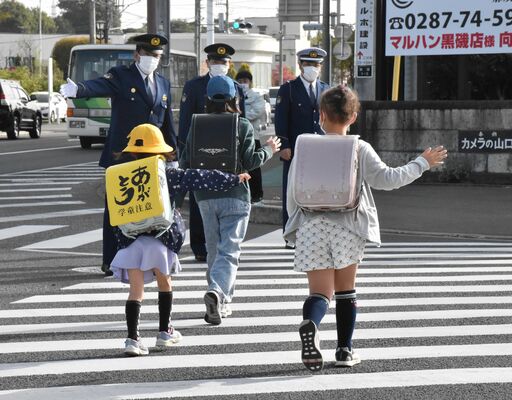 ランドセルに黄色のカバーを付けた新入児童らに交通指導する大田原署員