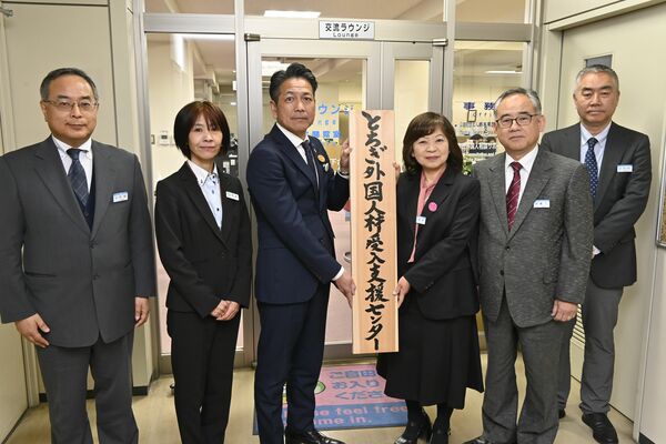 とちぎ外国人材受入支援センターの看板を掲げる県産業労働観光部の鱒渕部長（左から３人目）と県国際交流協会の野原恵美子理事長（同４人目）ら＝１日午後、宇都宮市