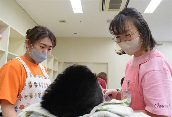 「今日も表情が明るいね」などと子どもに声を掛けながらケアを行う看護師の川俣さん（左）と杉野さん＝10月上旬、のざわ特別支援学校