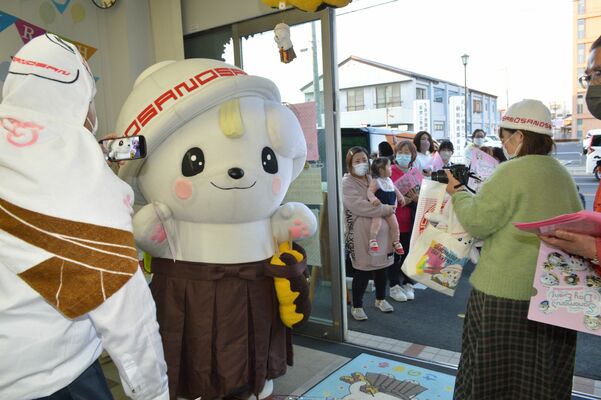 店舗から出て行く来場者を見送るさのまる