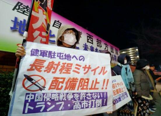 熊本市の陸自健軍駐屯地前で、長射程ミサイルの配備に反対する人たち=8日午後8時29分