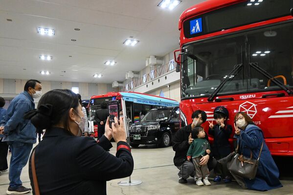 乗務員の服を着てバスの前で記念撮影する来場者ら=24日午後、宇都宮市元今泉6丁目