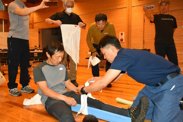 湯本分署員（右）から負傷者の手当ての方法を学ぶ参加者