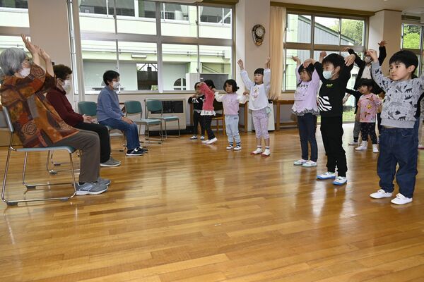 幼児たちのダンスに合わせて手を振るなどする参加者