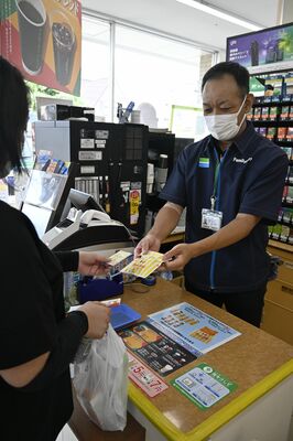 献血カードを示してファミチキレッドを受け取る協力者＝24日午後、宇都宮市越戸３丁目