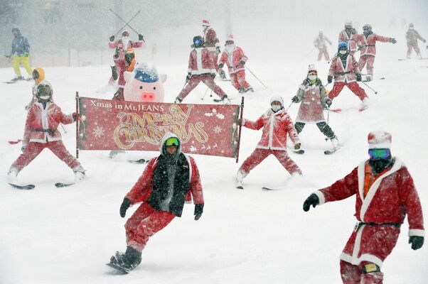 雪が降る中、サンタ姿で滑走する来場者たち＝24日午前10時30分、那須町大島