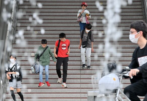 半袖など薄着で駅から出てくる人たち＝24日午後２時15分、佐野市若松町
