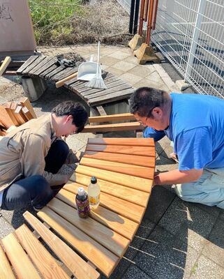 中央町３丁目のベンチの新装作業を行う和久井さん（右）ら