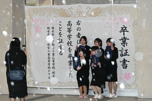巨大な卒業証書の前で記念撮影する生徒たち