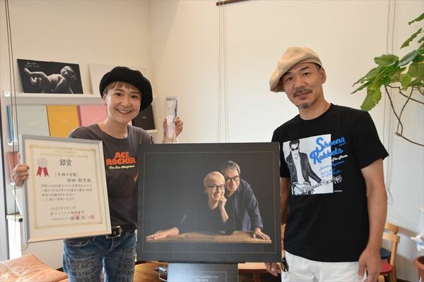 銀賞受賞作品を前に賞状などを手にする植田さん（左）と夫・光伸さん