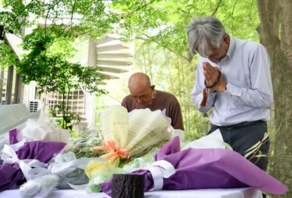 　空自機墜落事故から１年となり、献花台の前で手を合わせる人たち＝１４日午後、愛知県犬山市