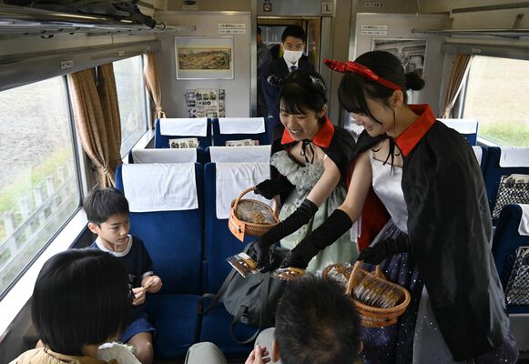 ＳＬの車内で子どもたちに焼き菓子を手渡す生徒