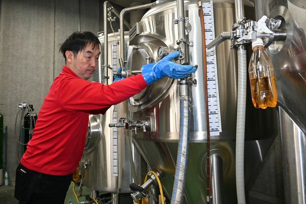 トレードマークになっている「赤いシャツ」を着てタンクを調整する石井さん＝足利市