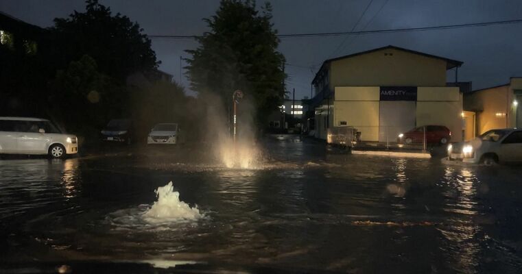 雨で冠水し水が噴き出す道路＝13日夜、宇都宮市横田新町（読者提供）