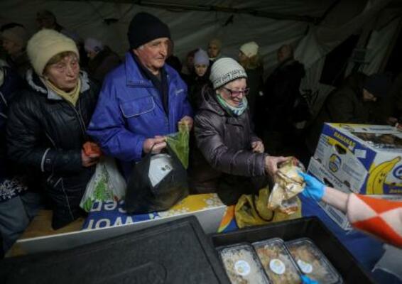　７日、ウクライナ・キーウで、政府が運営する住民支援テントで食事を受け取る人たち（ロイター＝共同）