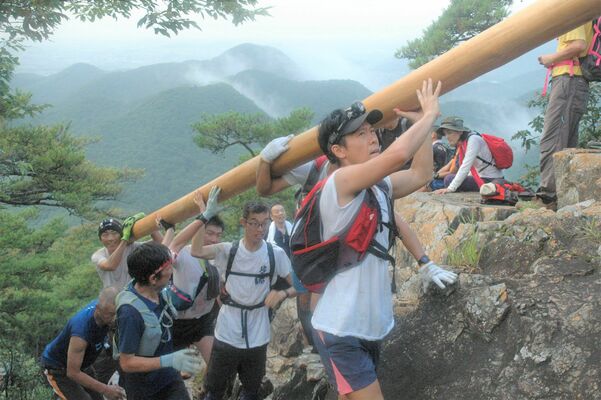 梵天祭りで巨大な丸太を運ぶ担ぎ手たち＝2019年８月14日撮影