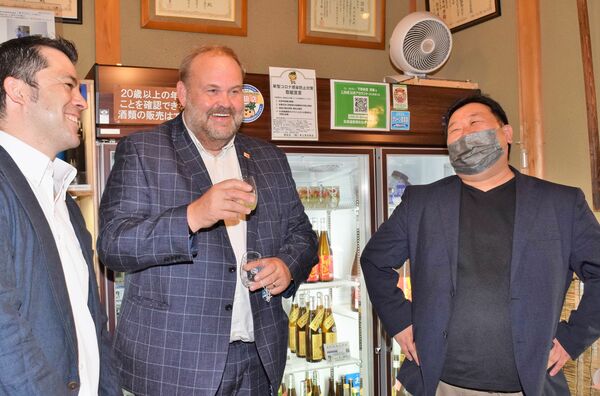 ２回目のチャンピオン・サケを受賞し井上清吉商店を訪れ、試飲するＩＷＣサケ部門責任者のクリス・アッシュトンさん（中央）＝２０２２年１０月、宇都宮市
