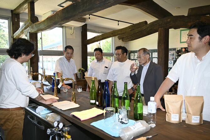 旧上粕尾小の売店で小林醸造の量り売り酒を試飲する全国青年会議所酒類部会のメンバー＝６月、鹿沼市