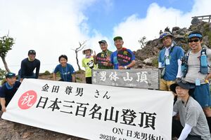 日本三百名山登頂を成し遂げ、山頂で仲間と記念撮影する金田さん（後列右から３人目）＝11日午前、男体山山頂