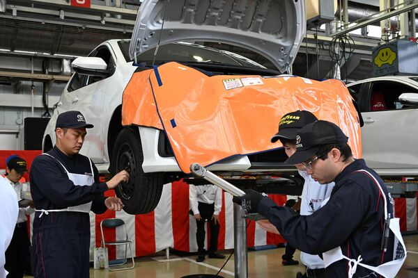 課題に応じて車両の整備を行う出場者ら＝22日午前、宇都宮市