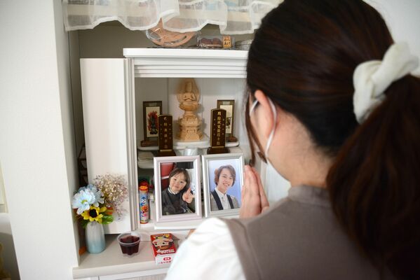 長男の湊斗ちゃん（左）と夫の寛人さんの遺影に手を合わせる女性＝８日午前、前橋市