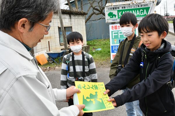 あんしん家を訪問し新しいステッカーを手渡す児童