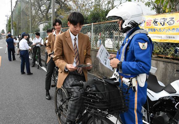 自転車で下校中の高校生に交通安全を呼びかける警察官ら＝25日午後、宇都宮市桜３丁目