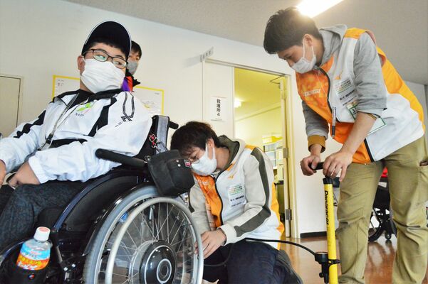 車いすや義足のメンテナンスに対応する石井さん（中央）と横山さん（右）＝30日午後、県総合運動公園第２陸上競技場