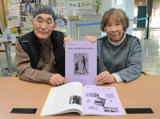 「栃木・宮沢賢治の会」の創立25周年記念誌を手にする小堀代表代行（左）と豊田副代表