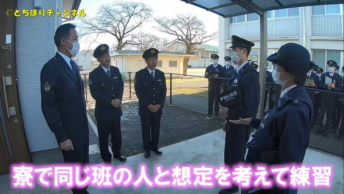 受験者募集動画の中で、家庭への巡回連絡を模擬体験するＵ字工事（左から２人目と３人目）（県警提供）