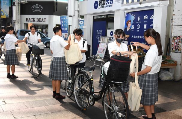 ワイヤーロックが入った防犯グッズを渡す文星女子高の生徒＝宇都宮市江野町、オリオンスクエア、午後１５時３５分